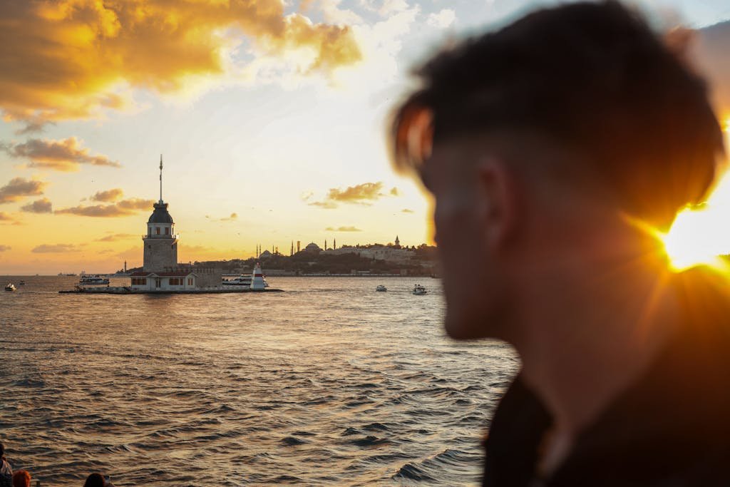 A silhouette in foreground with the historic Maiden's Tower against a stunning Istanbul sunset over the sea.