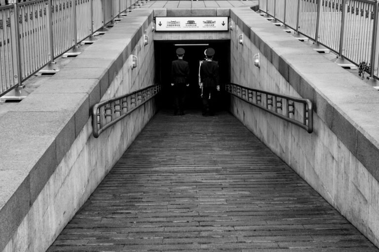 Black and white photo capturing two guards entering a tunnel in Beijing, China.